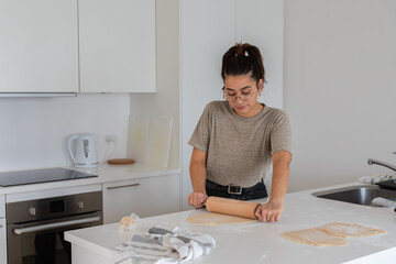 young black haired woman cooking happy homemade pasta by hand with rolling pin