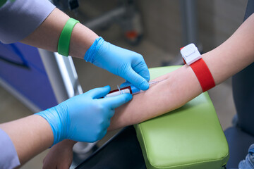 Nurse in protective gloves takes blood for analysis from patient