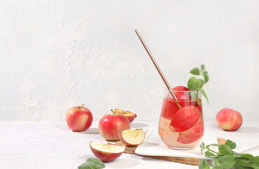 Apple cider, juice or fruit drink in a glass on a sunny table, autumn vitamin mulled wine with apple slices. The concept of diet and weight loss. Apples help cleanse the body and reduce weight.