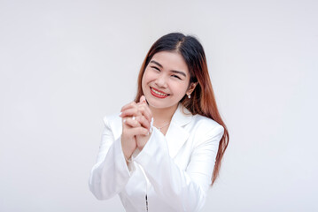 A friendly young woman smiling at the camera asking for a favor with hands clasped together. Isolated on a white background.