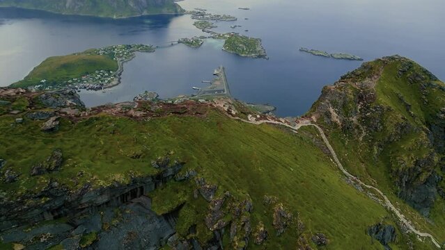 Drone zooms out to reveal an epic view of a fishing village on the water at the foot of the fjords