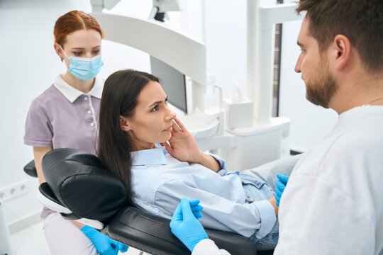Woman patient complaining to dentist on dull and constant toothache