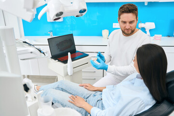 Professional stomatologist showing on 3d teeth model how treat decayed teeth