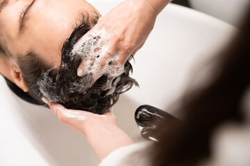 Hairdresser in the salon washes the hair of a man
