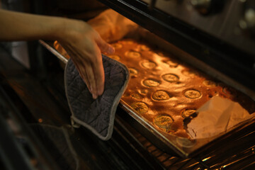 Cooking banana pie in the oven. A hand holds a hot baking sheet with a tongs