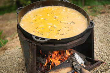 Cooking porridge with meat in a cauldron on an open fire, in nature