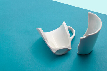 Detail of a broken cup on a blue background, representing vulnerability and disruption.