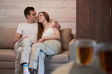 Obraz premium Man and lady hugging while sitting on sofa at home