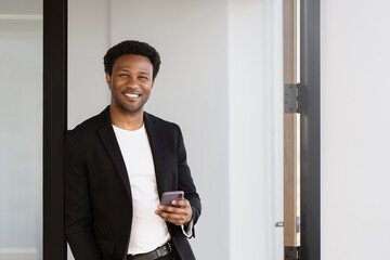 Smiling African man wearing stylish formal wear suit holding mobile phone online shopping