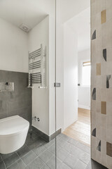 Walls of a tiled bathroom with modern decorative tiles, a wall hung toilet, square tiles on floors and walls