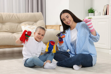 Happy mother and daughter playing with funny sock puppets together at home