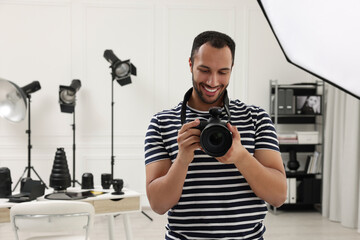 Young professional photographer with camera in modern photo studio, space for text