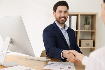 Human resources manager shaking hands with applicant during job interview in office