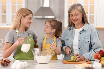 Three generations. Happy grandmother, her daughter and granddaughter cooking together in kitchen