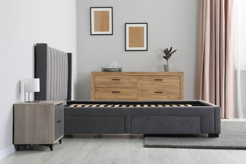 Comfortable bed with storage space for bedding under slatted base in stylish room - obrazy, fototapety, plakaty