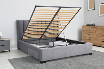 Comfortable bed with storage space for bedding under lifted slatted base in stylish room