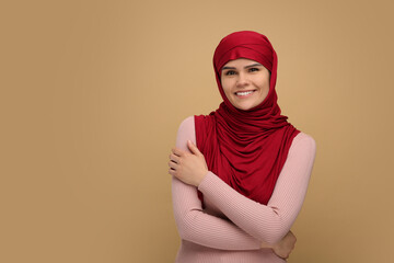 Portrait of Muslim woman in hijab on beige background, space for text