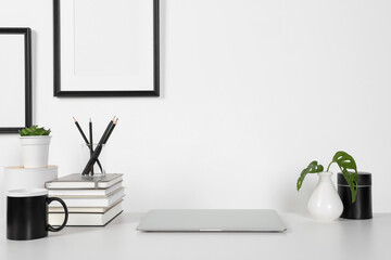 Home workplace. Laptop, stationery and houseplants on white wooden desk