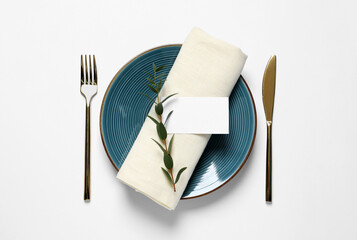 Stylish table setting with cutlery, blank card and eucalyptus leaves on white background, flat lay