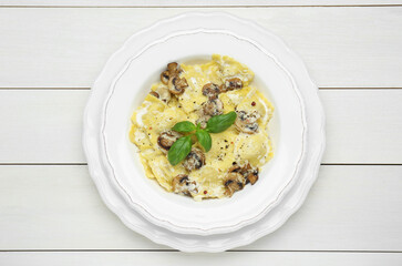 Delicious ravioli with mushrooms and cheese on white wooden table, top view