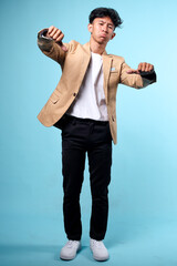 Young Asian man wearing casual blazer standing over isolated blue background looking unhappy,...