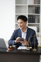 Young Asian legal officer working in his office room while having a phone call with his client.