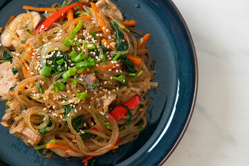 japchae or stir-fried Korean vermicelli noodles with vegetables and pork topped with white sesame
