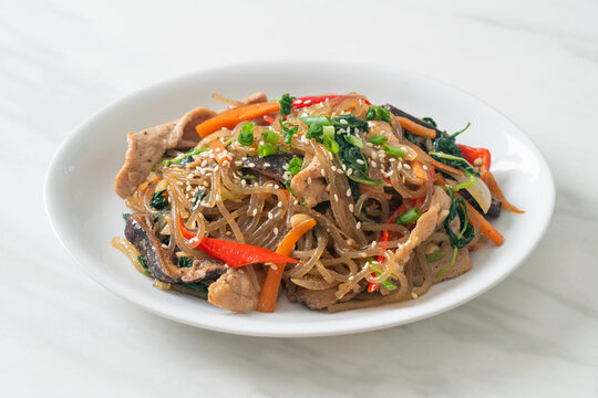 japchae or stir-fried Korean vermicelli noodles with vegetables and pork topped with white sesame