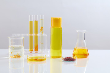 Unbranded bottle filled with liquid and arranged with laboratory glassware over white background. Saffron is the most expensive spice in the world