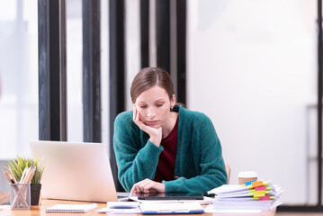 Businesswomen are stressed with work in front of a laptop and paper documents in the office.
