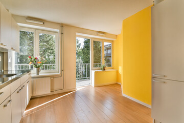 a kitchen with yellow walls and wood flooring in the middle of the room, there is an open door that leads to a