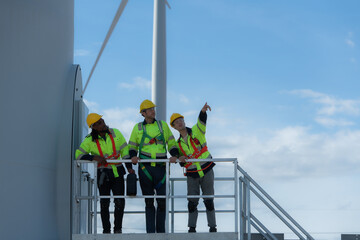 Group of engineers and technicians standing on the stairs of a wind turbine, The concept of natural energy from wind.