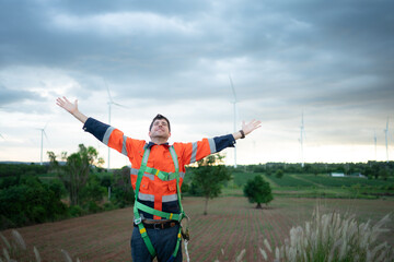 Young engineer working in a wind turbine field wear a safety vest raise both hands to relax after finishing the wind turbine inspection mission