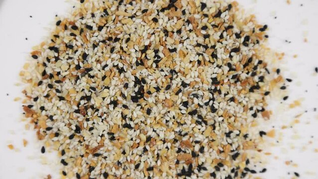 Everything bagel mix of garlic sesame seeds salt seasoning spinning clockwise - shallow depth of field