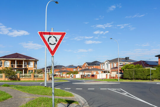 roundabout sign before road intersection in suburbia