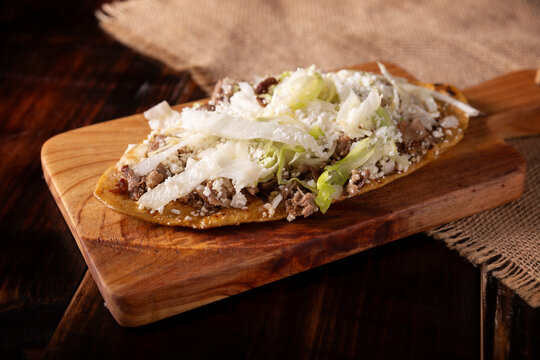 Huarache (food). Typical Mexican oval-shaped dish, made with corn dough and beans, commonly covered with lettuce, cheese, sauce and some protein such as steak, rib or egg.
