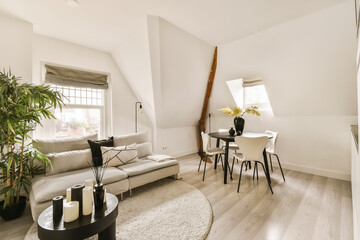 a living room with white walls and wood flooring in the center of the room there is a couch, coffee table, chair