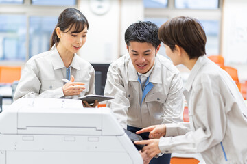 コピー機を点検する作業着を着た日本人