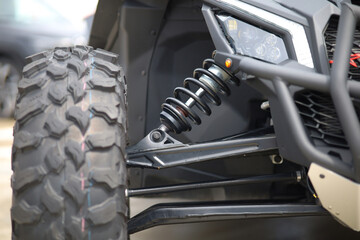 Close-up of new suspension system and shock absorber of car with wheel. Automotive part of atv off road. Mechanical engineering industry concept. 
