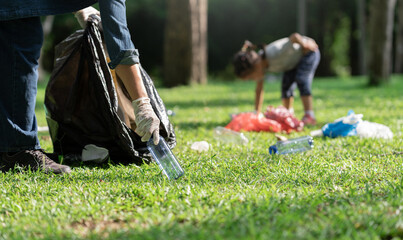 Youth volunteers, family volunteers put plastic bottles into black garbage bags. Clean the park, avoid pollution, be friendly to the environment and the ecosystem.