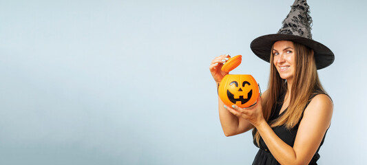 Happy young woman in halloween witch costume with pumpkin basket jack-o-lantern