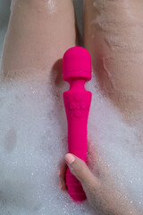 Woman lies in a bubble bath and uses a vibrator. 