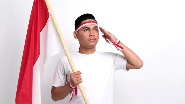 Handsome Asian men celebrate Indonesian independence day on 17 August, saluting and holding Indonesian flag isolated over white background