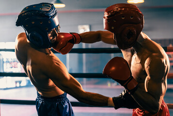 Two athletic and muscular body boxers with safety helmet or boxing head guard face off in fierce...