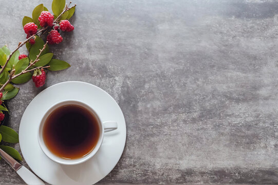 Cup of Tea and a sprig of Red Berries on a simple background
