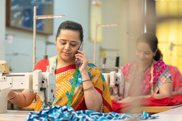 Indian woman talking on smartphone while working at textile factory.