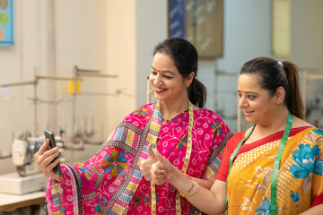 Indian women using smartphone at workplace, online learning concept.