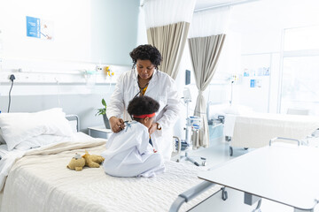 African american female doctor examining girl patient using stethoscope at hospital