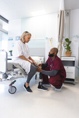 African american male doctor examining senior caucasian female patient with prosthetic leg