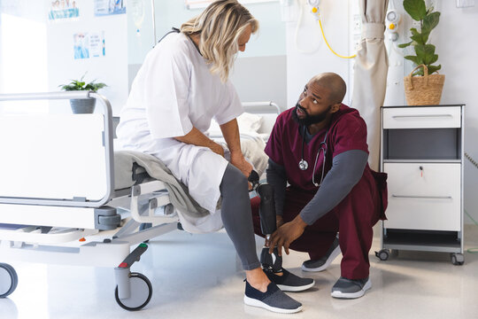 African american male doctor examining senior caucasian female patient with prosthetic leg